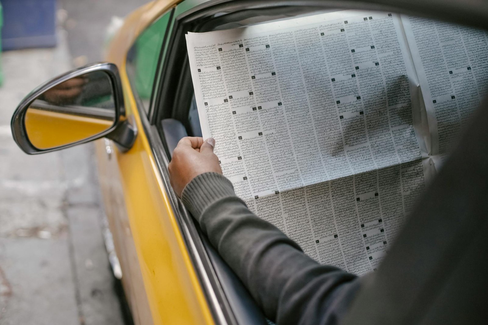 Person reading newspaper sitting in car