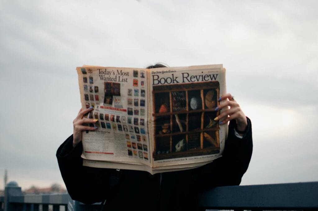 Person Holding White and Brown Newspaper