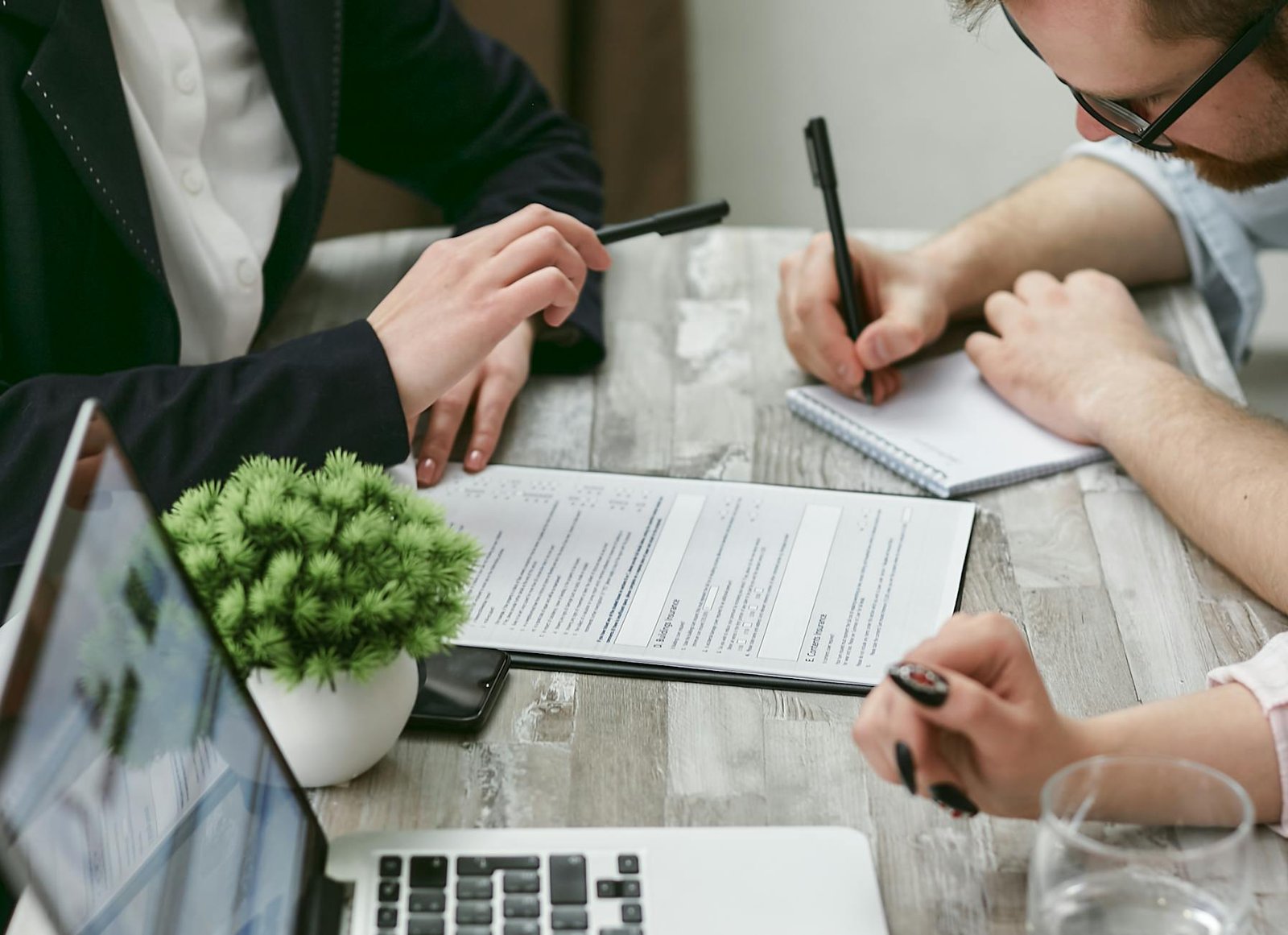 A Man with Eyeglasses Writing on a Notepad