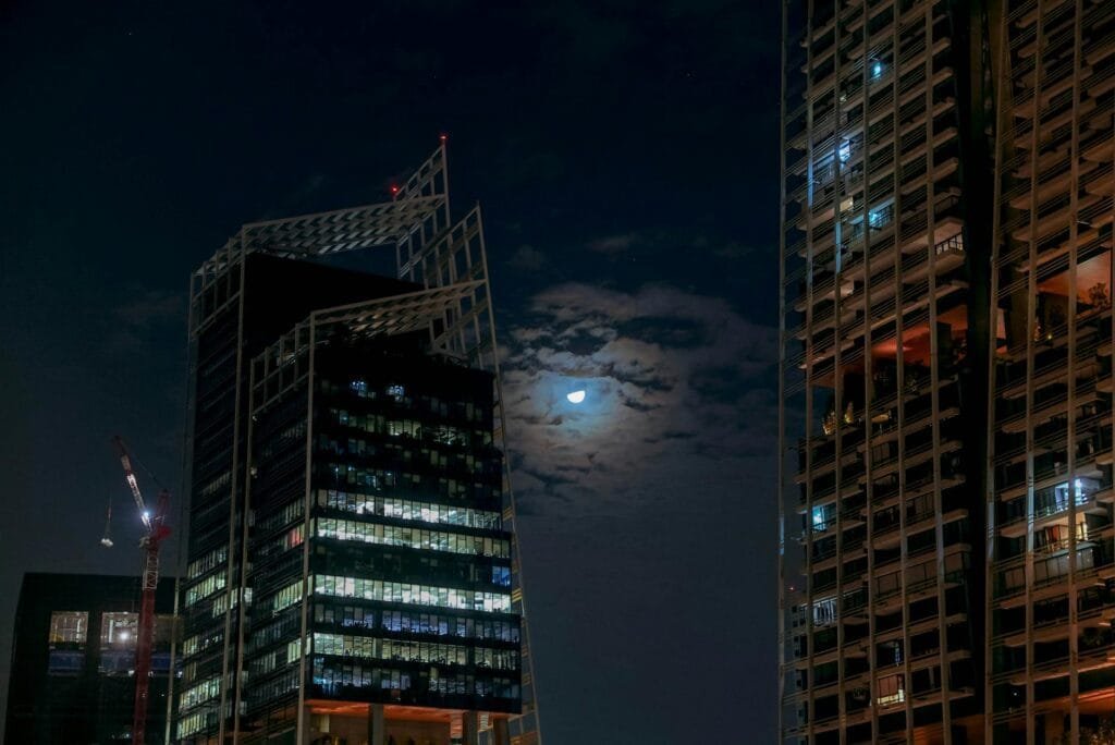 Moon in Night Sky near City Skyscrapers