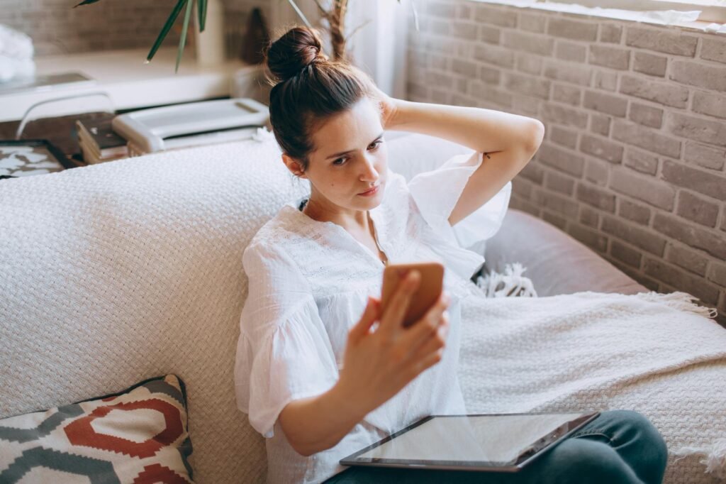 Woman Sitting on a Sofa and Taking a Selfie with her Smartphone