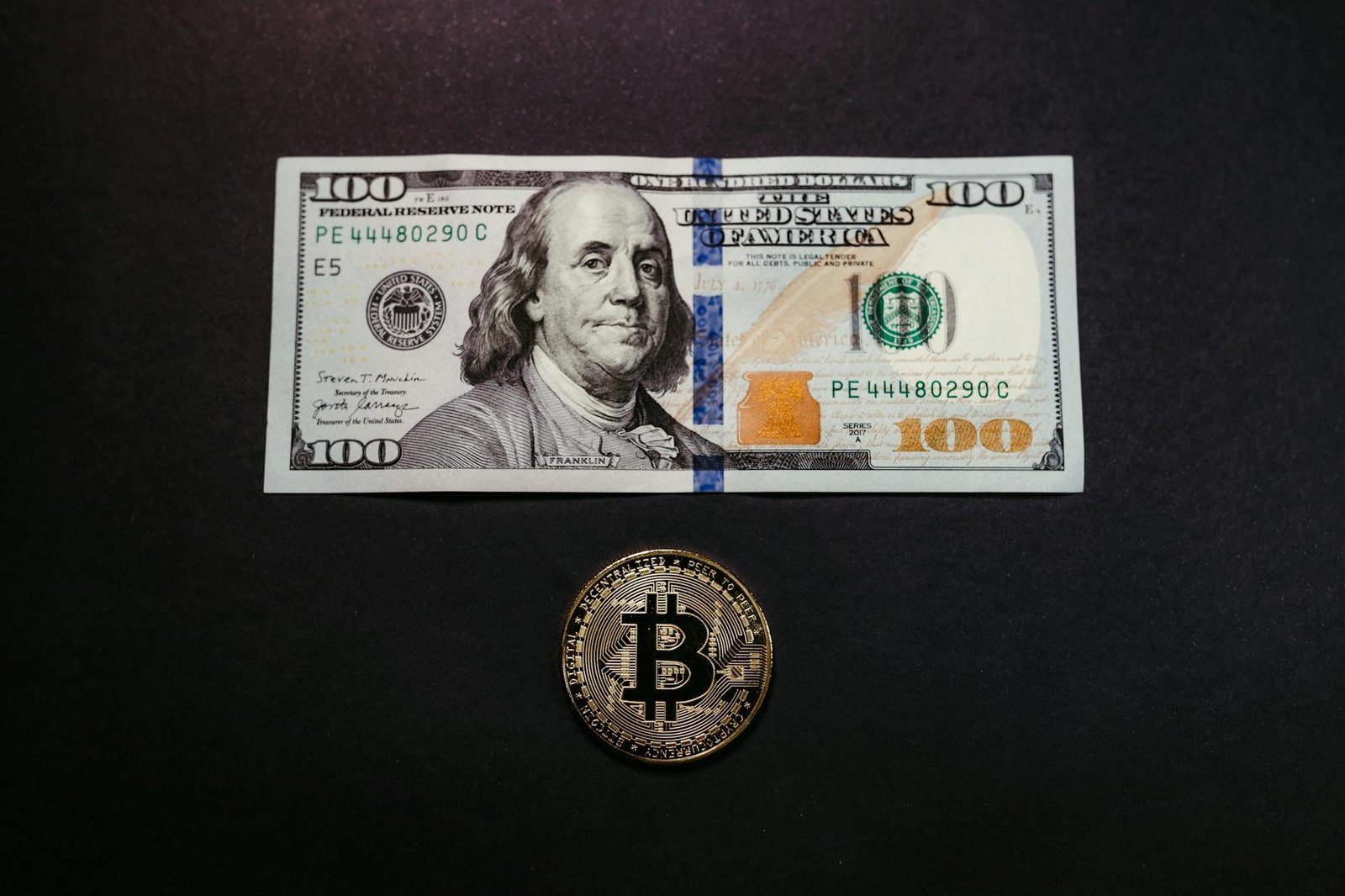 Close-Up Shot of Paper Money and Bitcoin on Black Surface