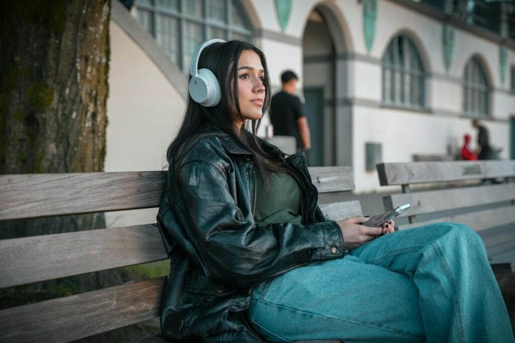 Woman With Headphones Sitting on Wooden Bench