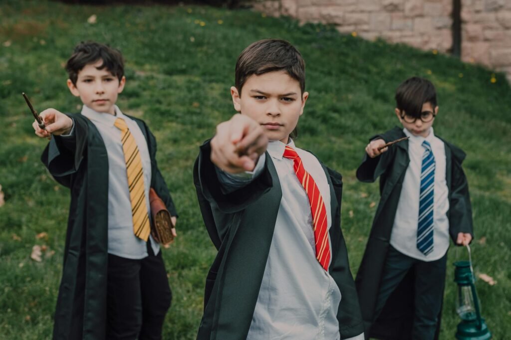 Three children in wizard costumes outdoors, casting spells with wands.