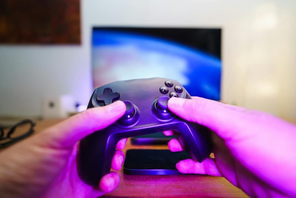 Close-up of hands holding a game controller in front of a TV screen. Perfect for entertainment setups.