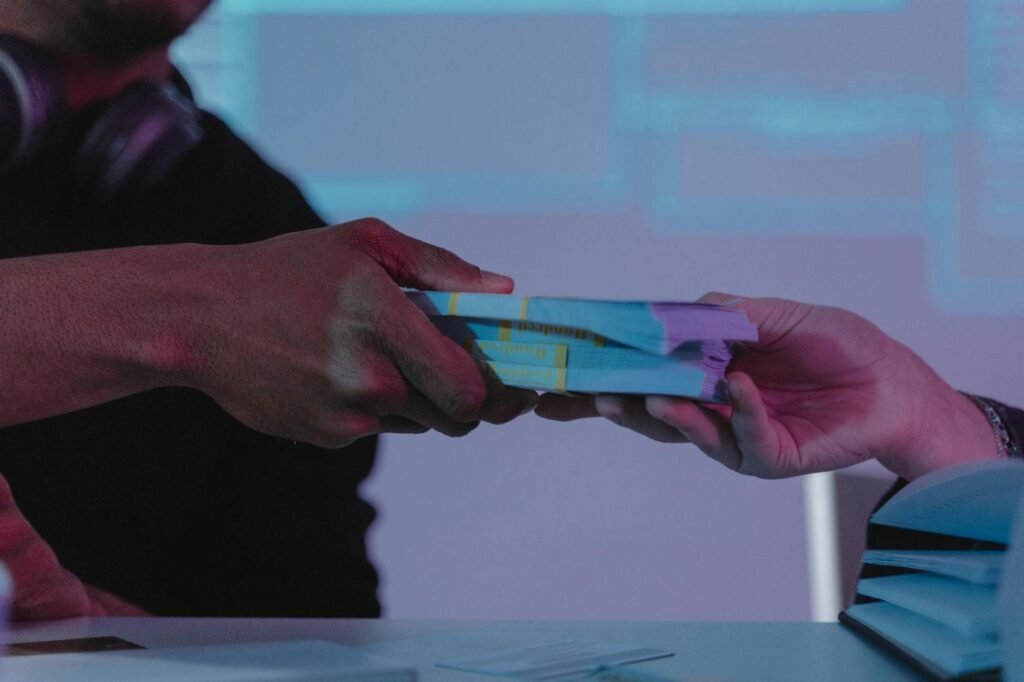 Close-up of hands exchanging money, highlighting financial exchange in a dimly lit setting.