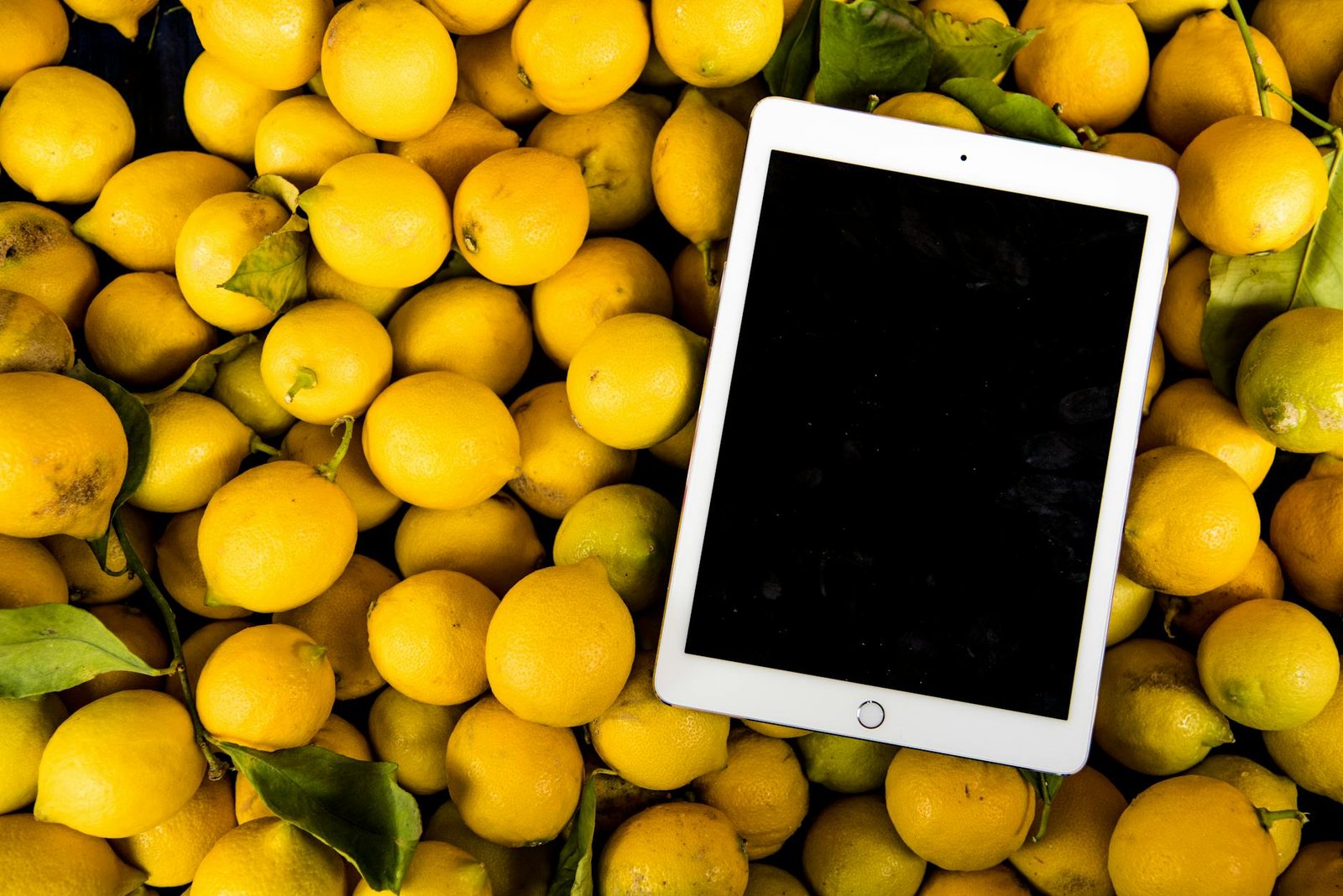 image A bright, fresh collection of lemons with a blank tablet screen for copyspace.