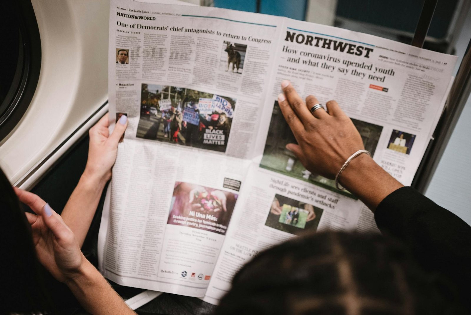 image People reading a newspaper on a subway train, highlighting current events and diverse perspectives.