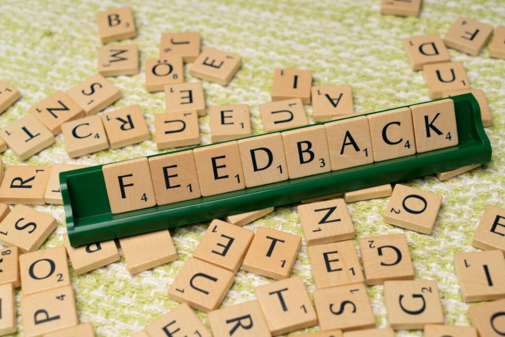 Wooden letter tiles spelling 'feedback' on a green rack, representing communication and evaluation.