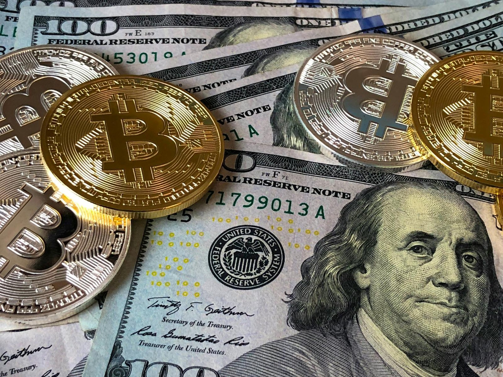 image A close-up photo depicting Bitcoin coins on top of US dollar bills, symbolizing finance and cryptocurrency.
